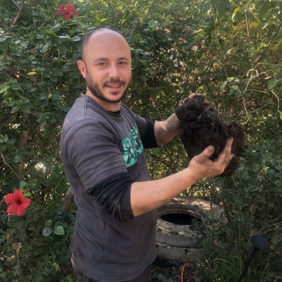 אדם מחזיק גוש אדמה ליד משאית ואקום