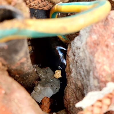 צינור גומי צבעוני בין אבנים עם מים