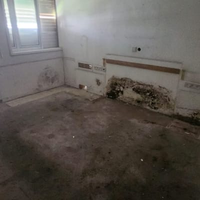 חדר ריק עם מאוורר תקרה וקירות עם כתמי רטיבות