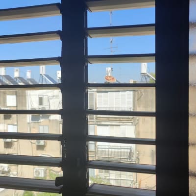 תריסים אופקיים פתוחים עם נוף עירוני ברקע