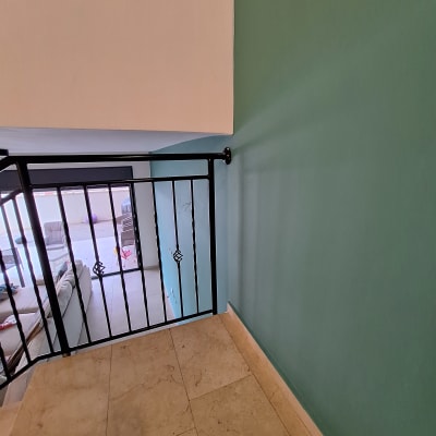 קיר צבוע בצבע ירוק בהיר ליד מעקה ברזל שחור