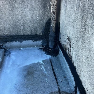 איטום גג עם חומר שחור סביב צינור וקירות