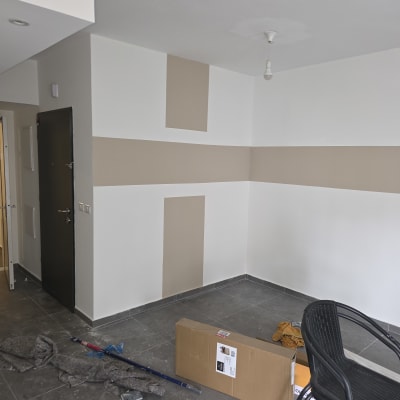 חדר צבוע עם קירות בצבעים שונים וכלי עבודה על הרצפה