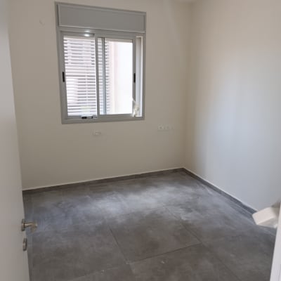 חדר מגורים משופץ וריק עם ריצוף גרניט פורצלן אפור וקירות צבועים