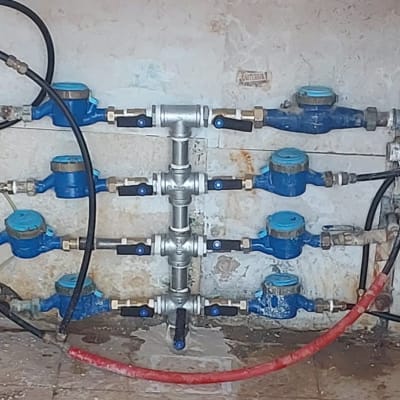 מד מים כחולים וצינורות מחוברים לקיר