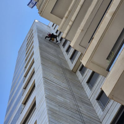 אדם עם קסדה מטפס על בניין גבוה בעזרת חבלים