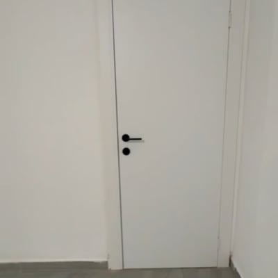 דלת לבנה עם ידית שחורה על קיר לבן