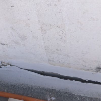 סדק בקיר עם צינור כתום על הרצפה