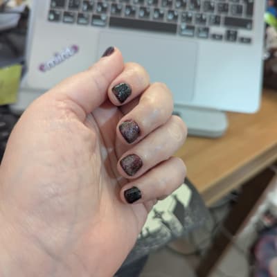 יד עם ציפורניים מטופחות על רקע מחשב נייד