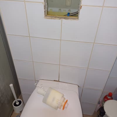 מיכל הדחה מונח על אסלה, פתח בקיר חשוף