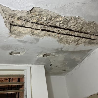 תקרה מתקלפת עם סדקים וחלון קטן