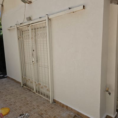 קיר משופץ עם דלת מתכת, שאריות צבע על הרצפה