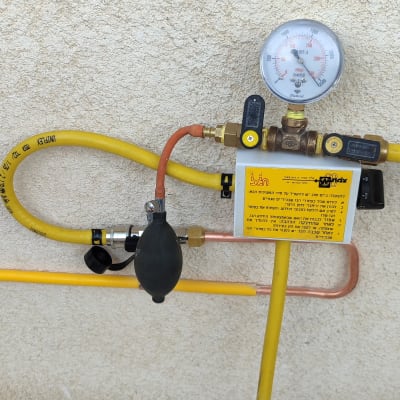 מד לחץ גז עם צינורות צהובים על קיר