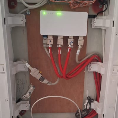 ארון תקשורת עם כבלים אדומים ולבנים מחוברים לנתב