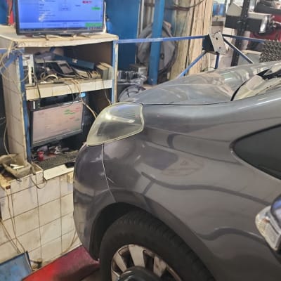 רכב במוסך עם ציוד בדיקה ומסך מחשב