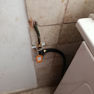 צינור גז מחובר לקיר ליד מכונת כביסה