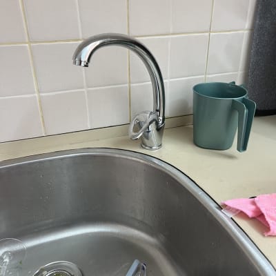 ברז נירוסטה מעל כיור מטבח עם כלים