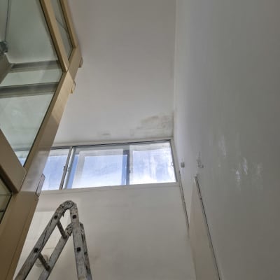 סולם מתכת ליד קיר צבוע בלבן