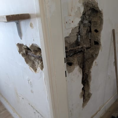 קיר עם חור גדול וצינורות חשופים