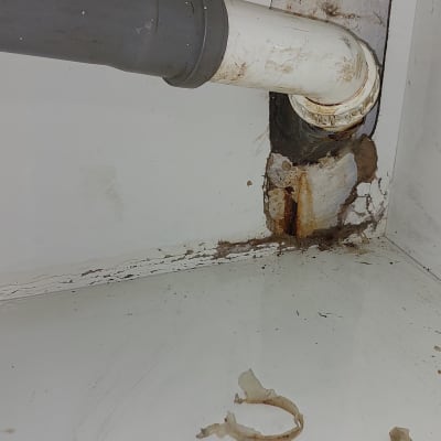 צינור פלסטיק לבן עם חיבור אפור בקיר