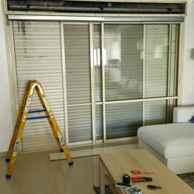 סלון עם תריסים, סולם וכלי עבודה על שולחן