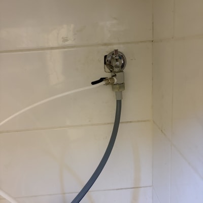 ברז וצינורות במטבח על קיר לבן