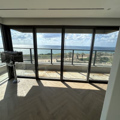 חדר עם רצפת עץ ונוף לים דרך חלונות גדולים
