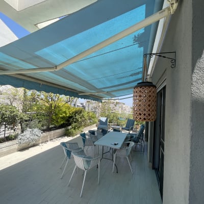 מרפסת עם סוכך כחול ושולחן וכיסאות