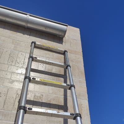 סולם מתכת ליד צינור על קיר בניין