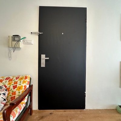 דלת שחורה עם ידית כסופה וקיר לבן