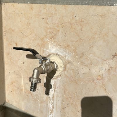 ברז מתכת מותקן על קיר אבן