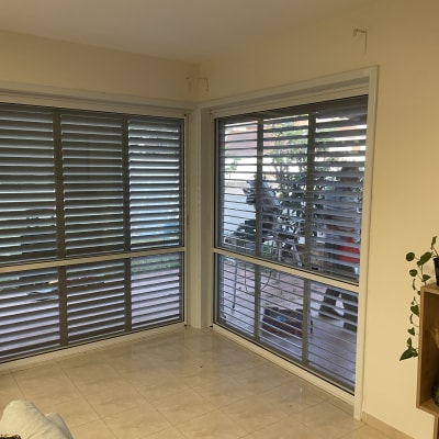 חלונות עם תריסי אלומיניום אפורים בחדר פנימי