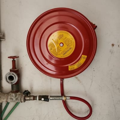 גלגלון כיבוי אש אדום עם צינור מחובר לקיר
