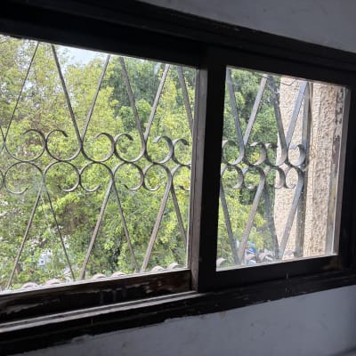 חלון עם סורגי ברזל ונוף עצים בחוץ