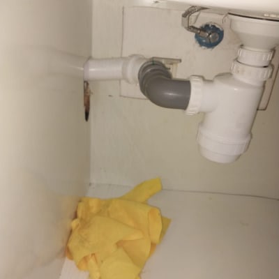 צנרת מתחת לכיור עם חיבורי פלסטיק ובד צהוב