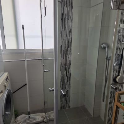 מקלחת עם דלת זכוכית, ראש מקלחת ומכונת כביסה