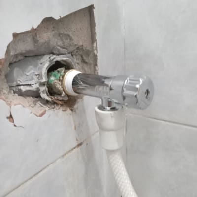 ברז מתכת מותקן בקיר עם צינור לבן