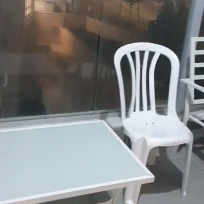 כיסא פלסטיק לבן ושולחן במרפסת