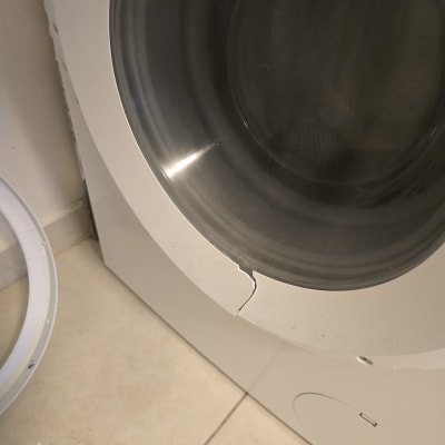 מכונת כביסה עם דלת שבורה על רצפה