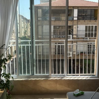 חלון זכוכית עם וילון לבן ונוף לבניינים בחוץ