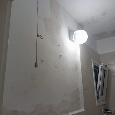 קיר עם תיקוני צבע ותאורה בחדר אמבטיה