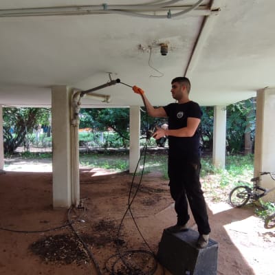 אדם עם כפפות כתומות עובד על צינור תקרה