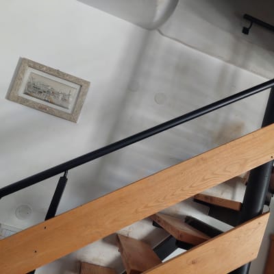 תמונה ממוסגרת תלויה על קיר לבן ליד מדרגות עץ