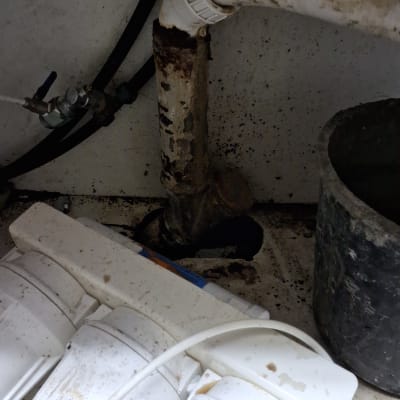 צינור מים עם חלודה וחיבורים מתחת לכיור