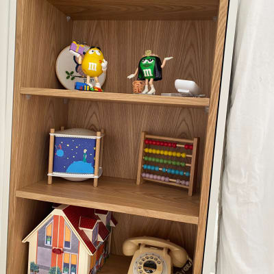 מדף עץ עם צעצועים, טלפון ישן ומחשבונים