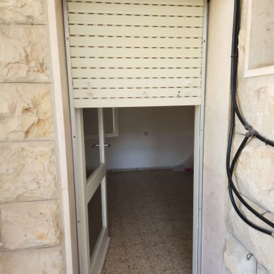 תריס לבן מותקן בפתח דלת אבן