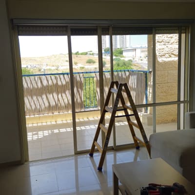 סולם וכלי עבודה ליד חלון עם תריסים