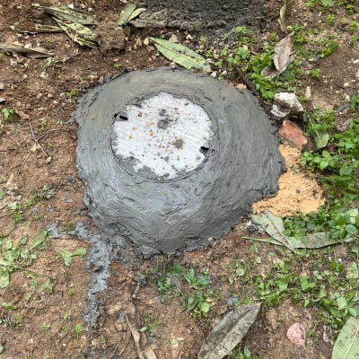 תמונה של מכסה ביוב עם בטון מסביבו על אדמה