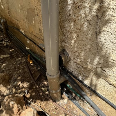 צינור פלסטיק חום מחובר לקיר עם צינורות נוספים