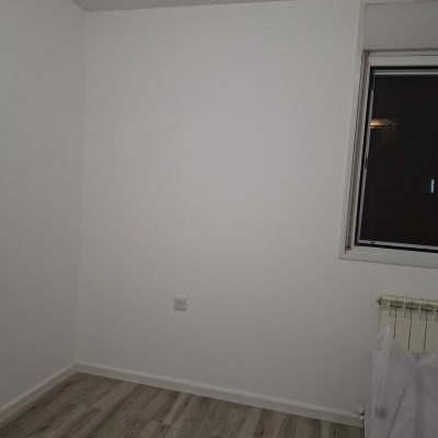 קיר לבן עם שקע חשמל ורצפת עץ